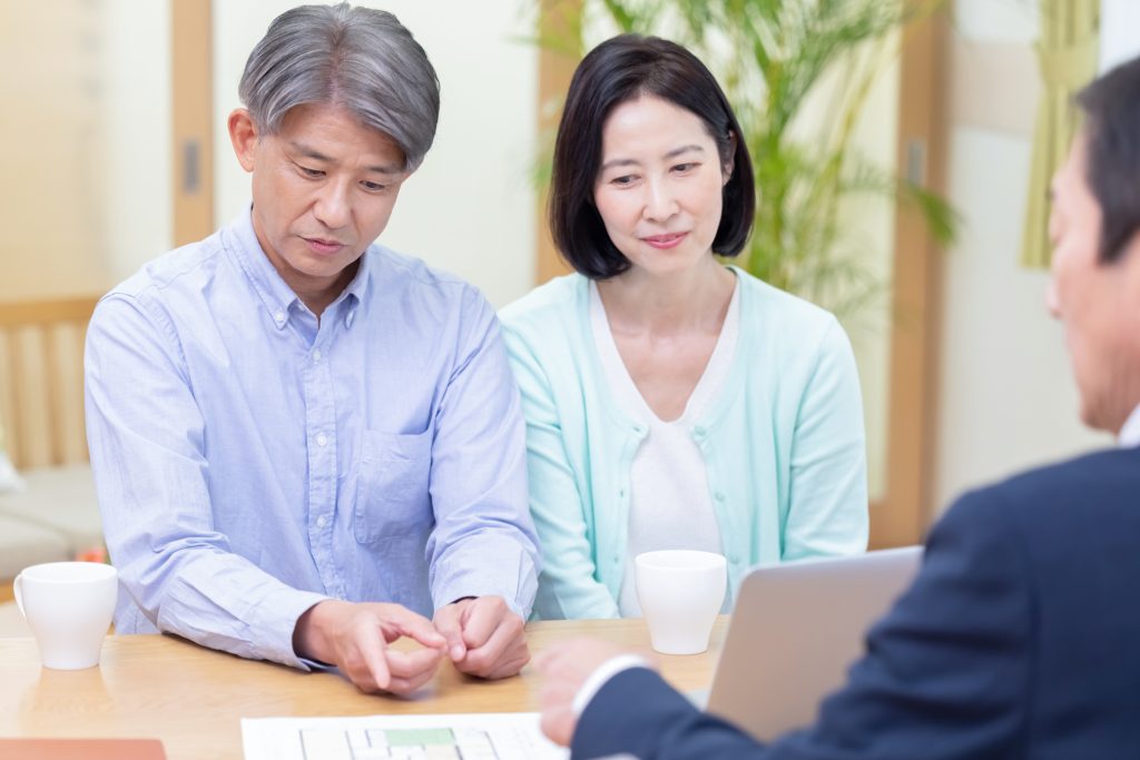テーブル越しに担当者の話を聞く、笑顔のミドル世代の夫婦