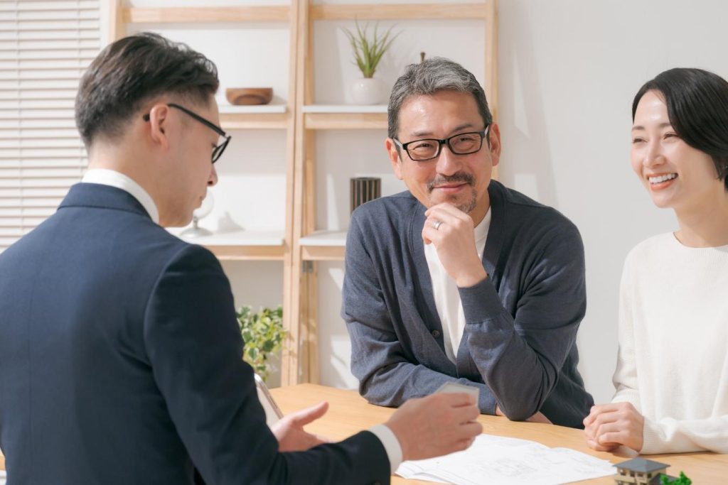 営業担当者と笑顔で打ち合わせをする夫婦