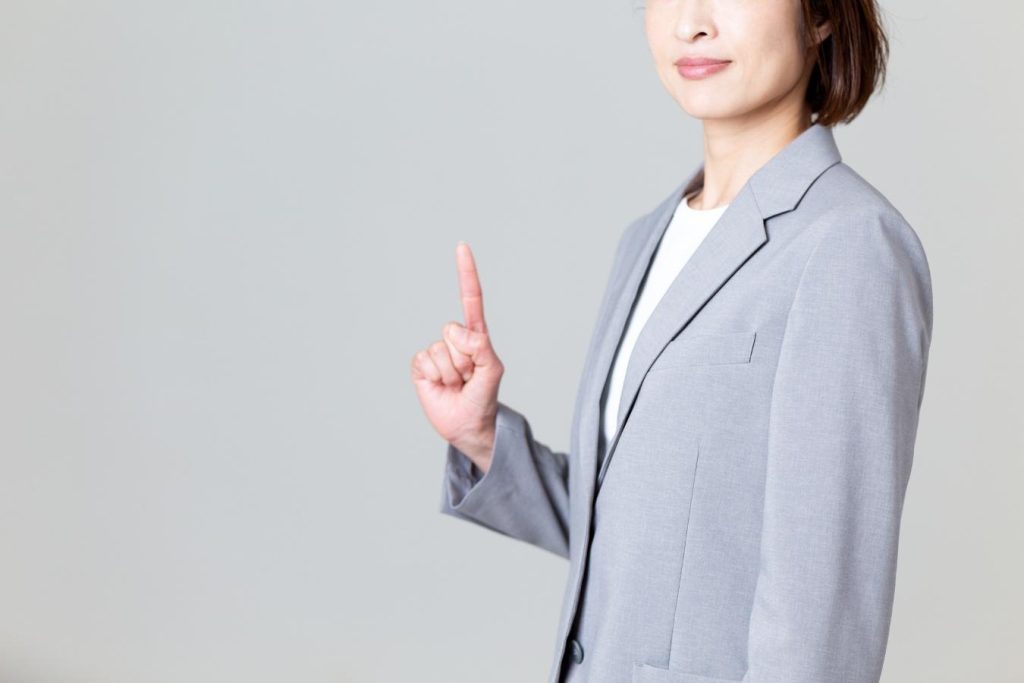 人さし指を立てる女性のビジネスパーソン。