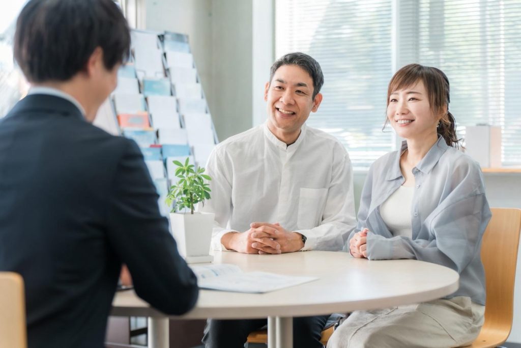 営業担当者と笑顔で打ち合わせをする夫婦