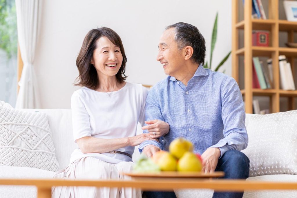 リビングのソファに座り、笑顔を浮かべる夫婦