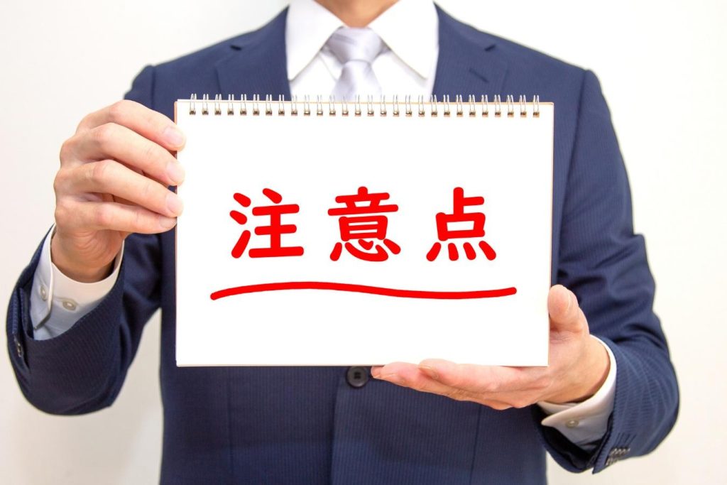 「注意点」を書かれたノートを持つ男性の手元