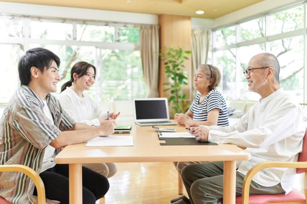向かい合って話し合いをする若い夫婦とシニア夫婦