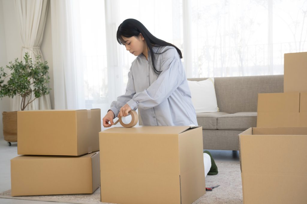 段ボールを組み立てて引っ越し作業をする女性