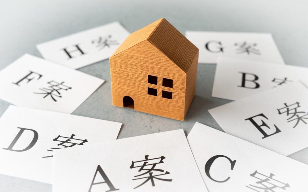 家の模型と「A案」「B案」などと書かれた複数の紙