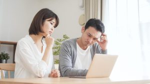 パソコンを見ながら考え事をする夫婦