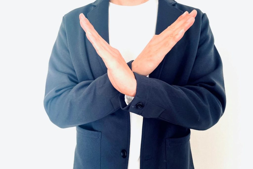 手でバツマークを作る男性。