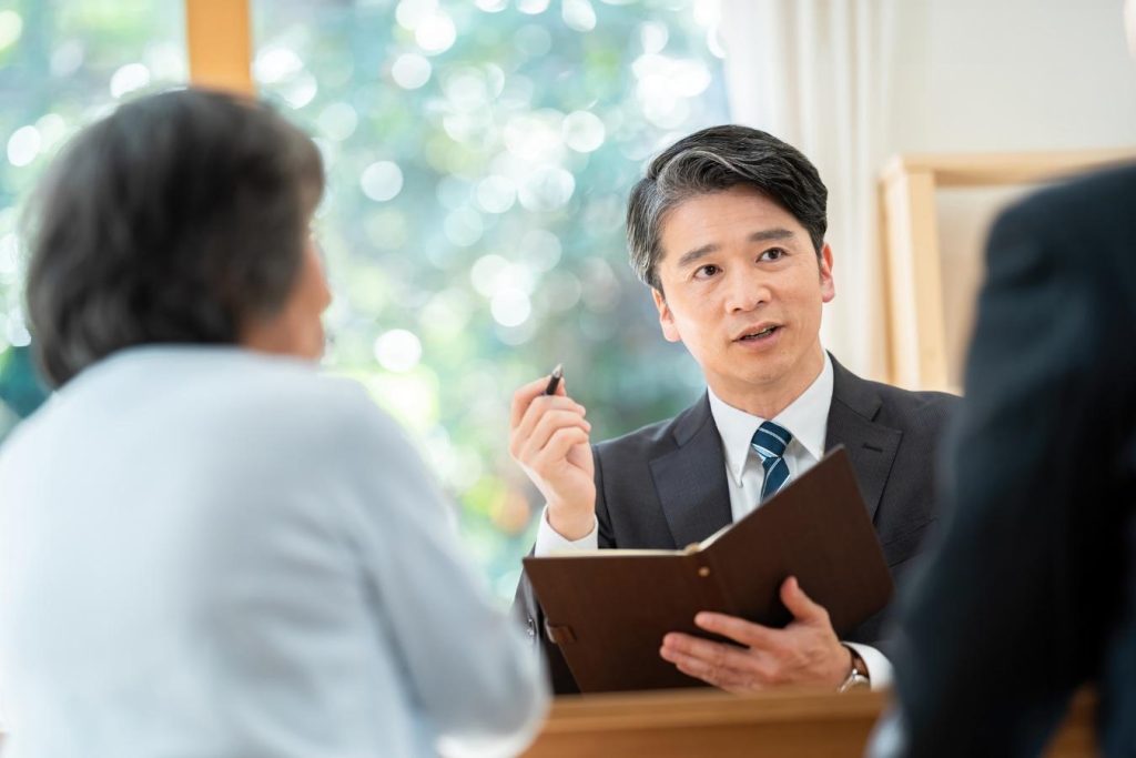 シニア夫婦から相談を受けるスーツの男性