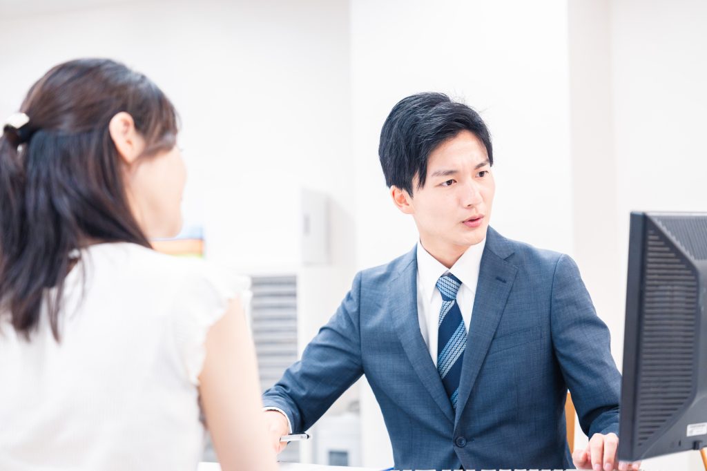 不動産会社のカウンターで相談する女性