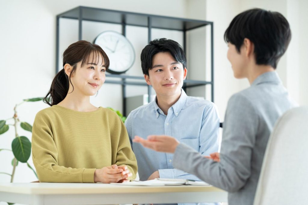 自宅で営業担当者と向かい合い、笑顔で話を聞く夫婦