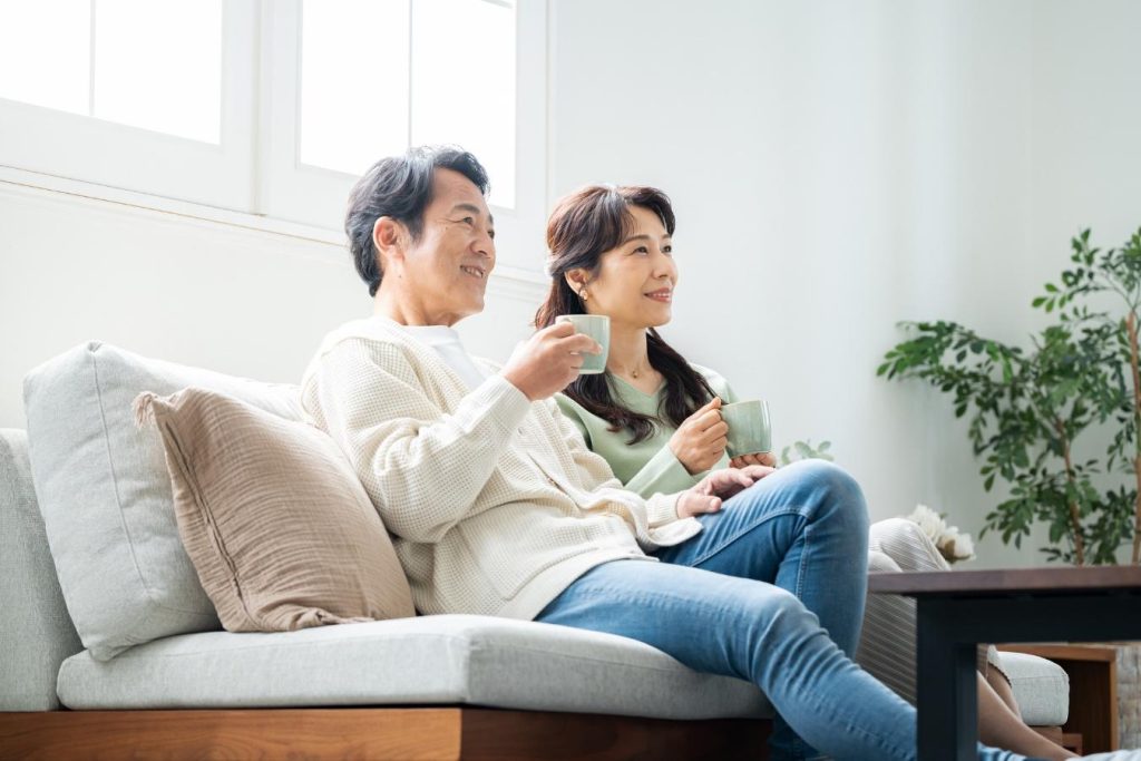 マグカップを手にリビングのソファで寛ぐ夫婦