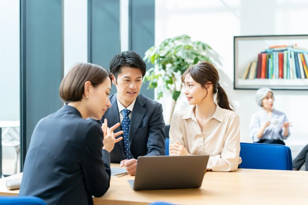 パソコンを見ながら相談する夫婦とスーツ姿の女性