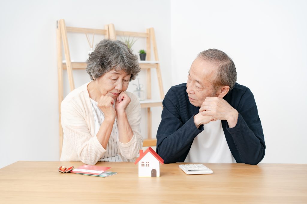 住宅模型を前に不動産について悩むシニア夫婦
