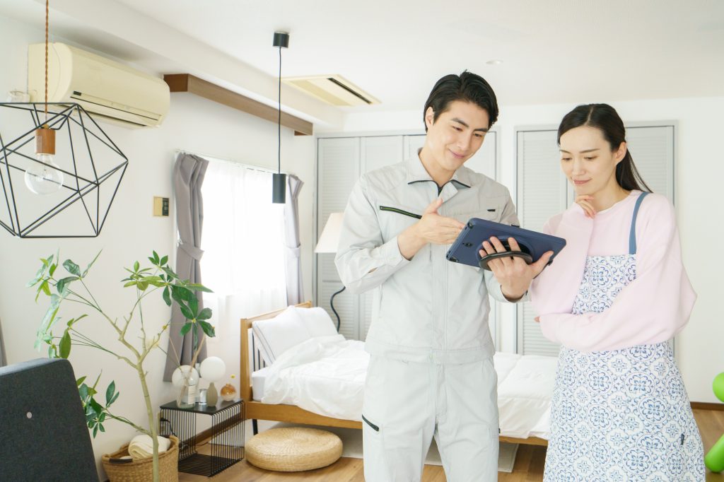 室内で作業員からタブレットを使ってリフォームの説明を受ける女性