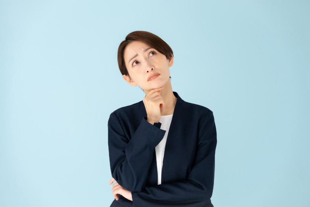顎に手を当てて考え込むスーツ姿の女性