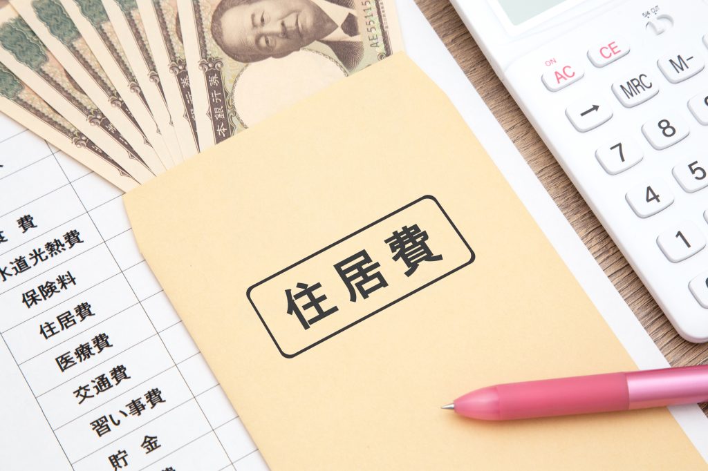 『住居費』と書かれたファイルと、日本円の紙幣、電卓、家計チェックリスト