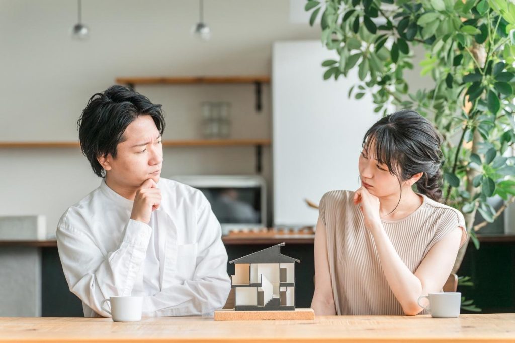 家の模型と悩む夫婦。