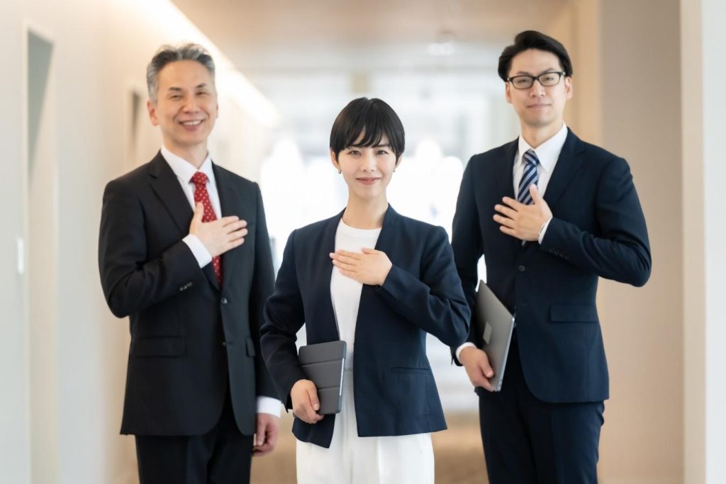 胸に手を当てるビジネスパーソンたち