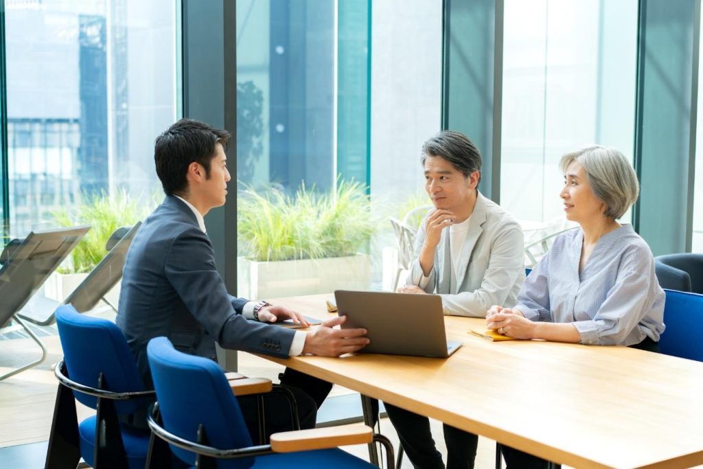 パソコンの画面を提示する専門家と向かい合い、話し合いをする夫婦
