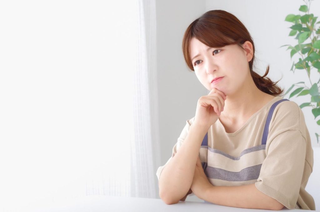 頬杖をついて考え事をするエプロン姿の女性。