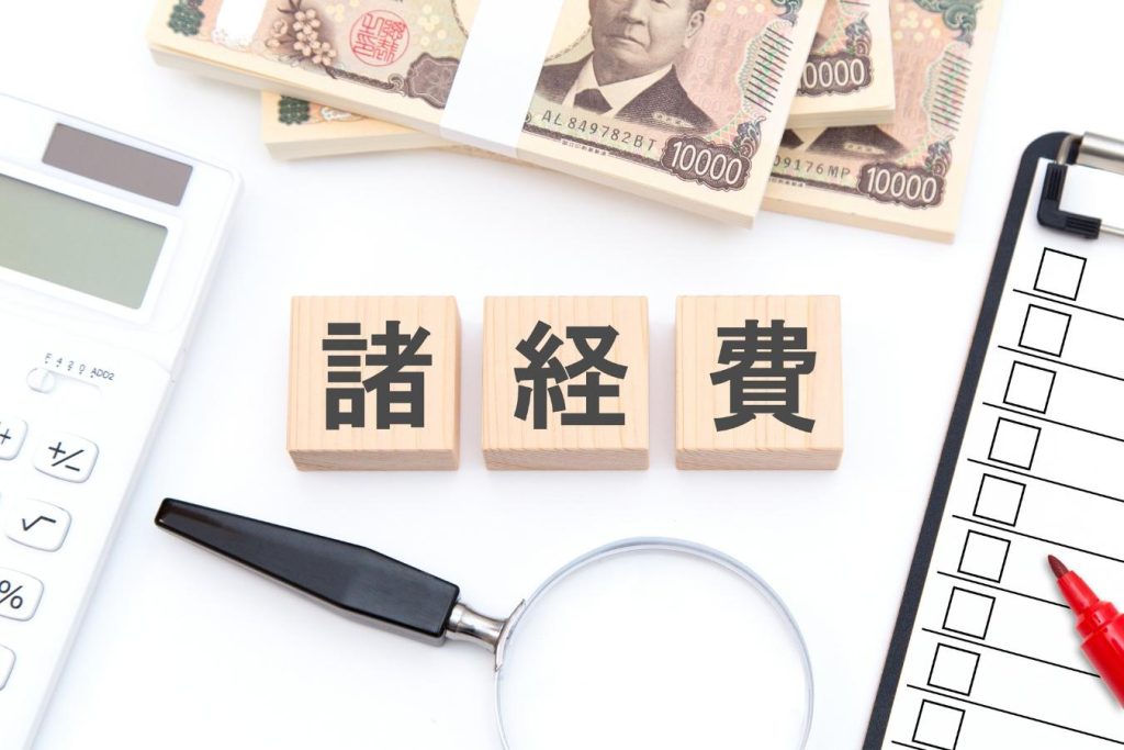 「諸経費」と書かれた木のブロックとチェックリスト、虫眼鏡、電卓