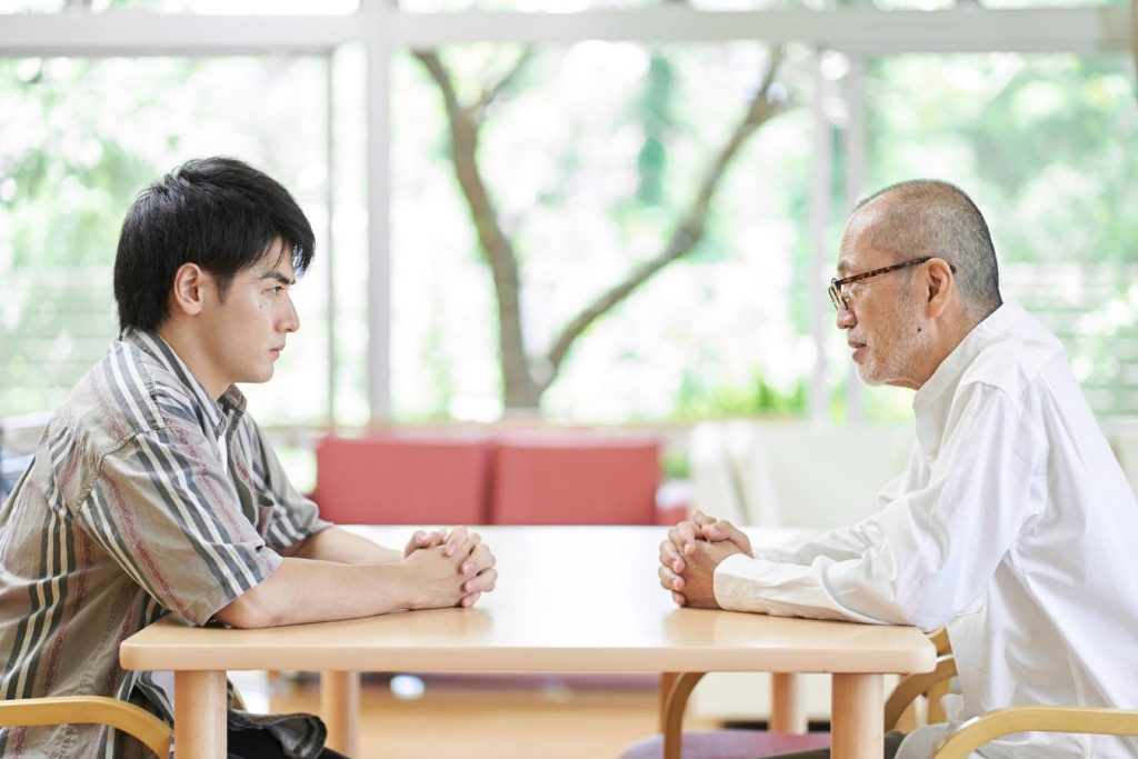 向かい合って話し合う若い男性とシニア男性