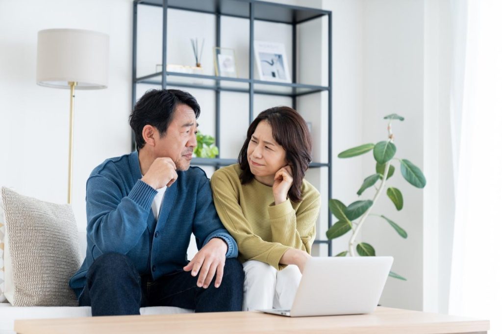 パソコンを前に、顔を見合わせて悩む夫婦
