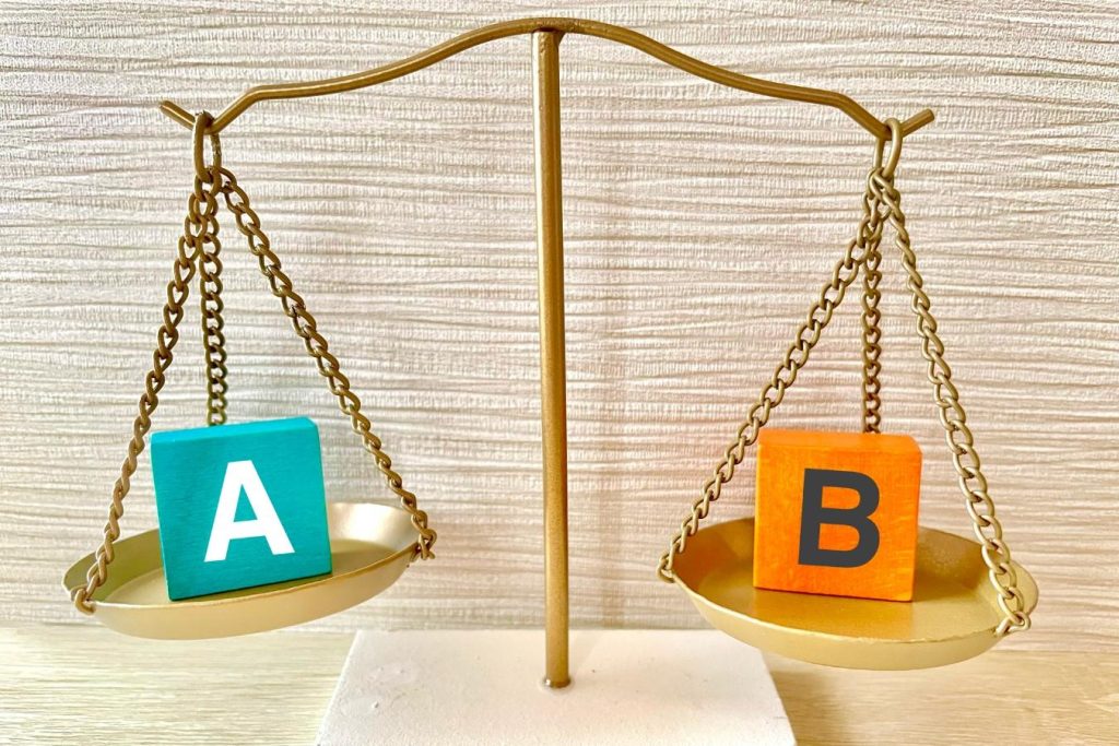 天秤の左右に「A」「B」と書かれた箱が乗る様子