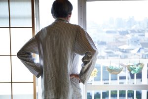 窓辺から外を眺める一人暮らしの高齢男性
